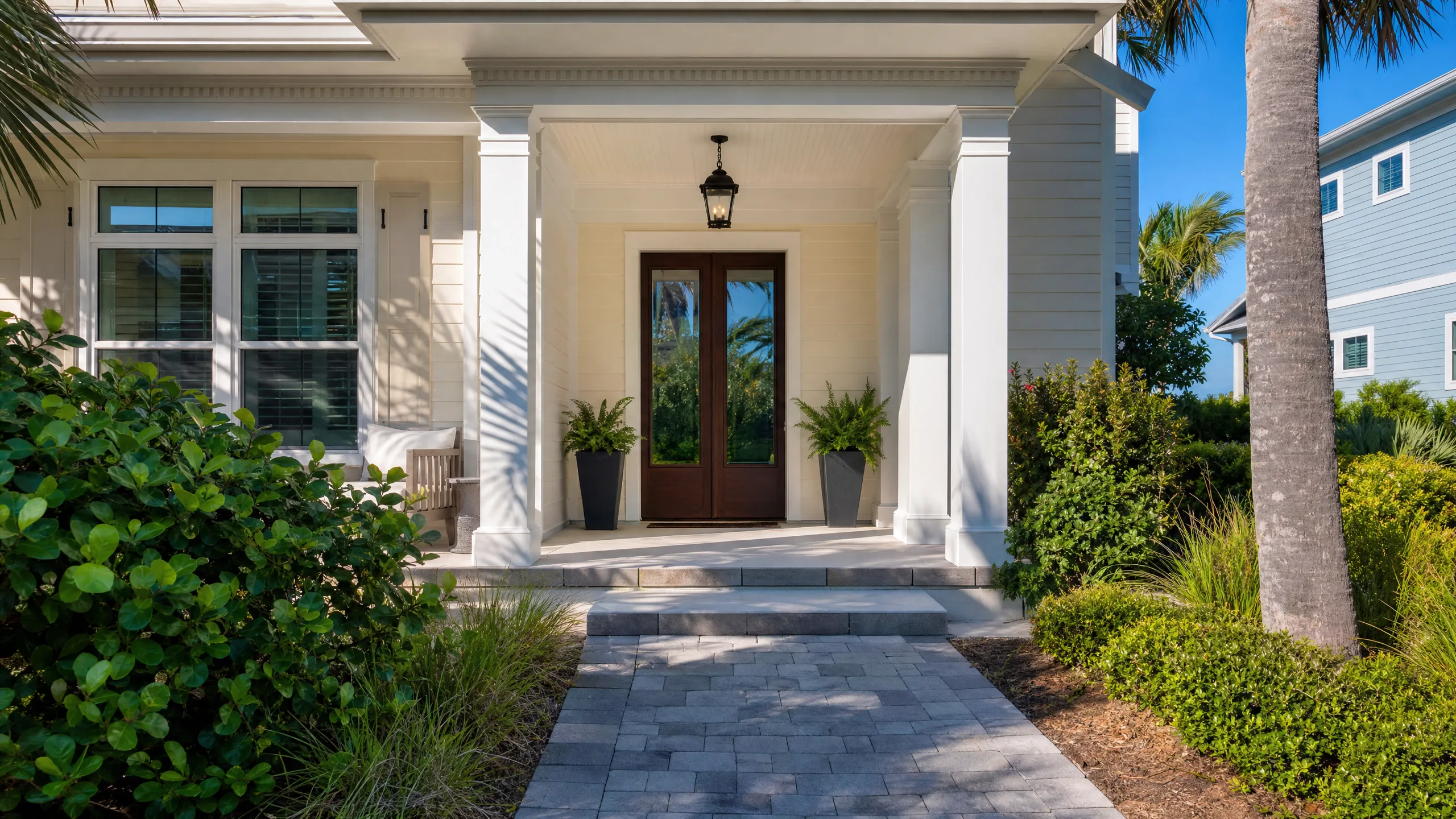 Coastal Florida front entry with a clean covered porch, front door, and tidy walkway in bright natural light